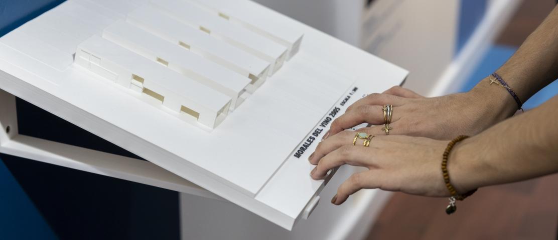 Imagen de dos manos tocando una maqueta de un edificio impreso en 3D