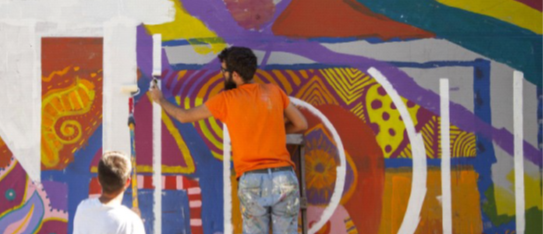 Imagen de dos personas pintando un mural en una pared