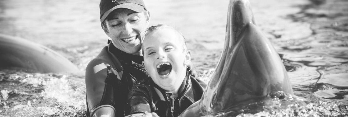 Fotografía del niño Ioan Inchusta feliz nadando con delfines y una monitora