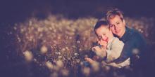 Imagen del niño Ioan Inchusta sonriente, en el campo, abrazado por su madre