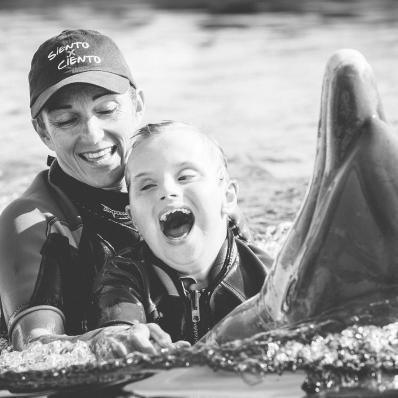 Fotografía del niño Ioan Inchusta feliz nadando con delfines y una monitora